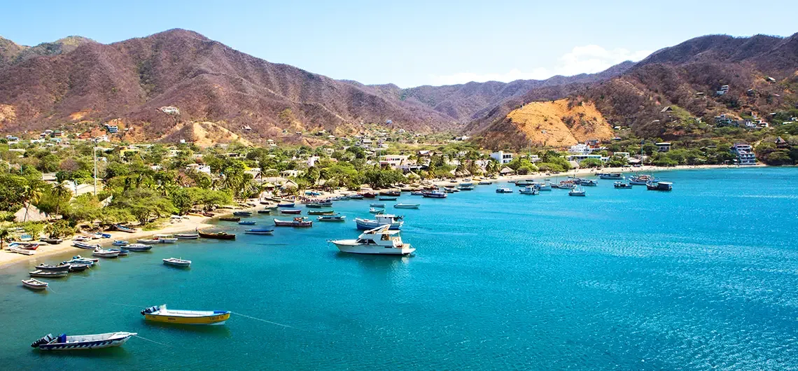 Bahía de Taganga con lanchas de pescadores, el pueblo y las montañas detrás.